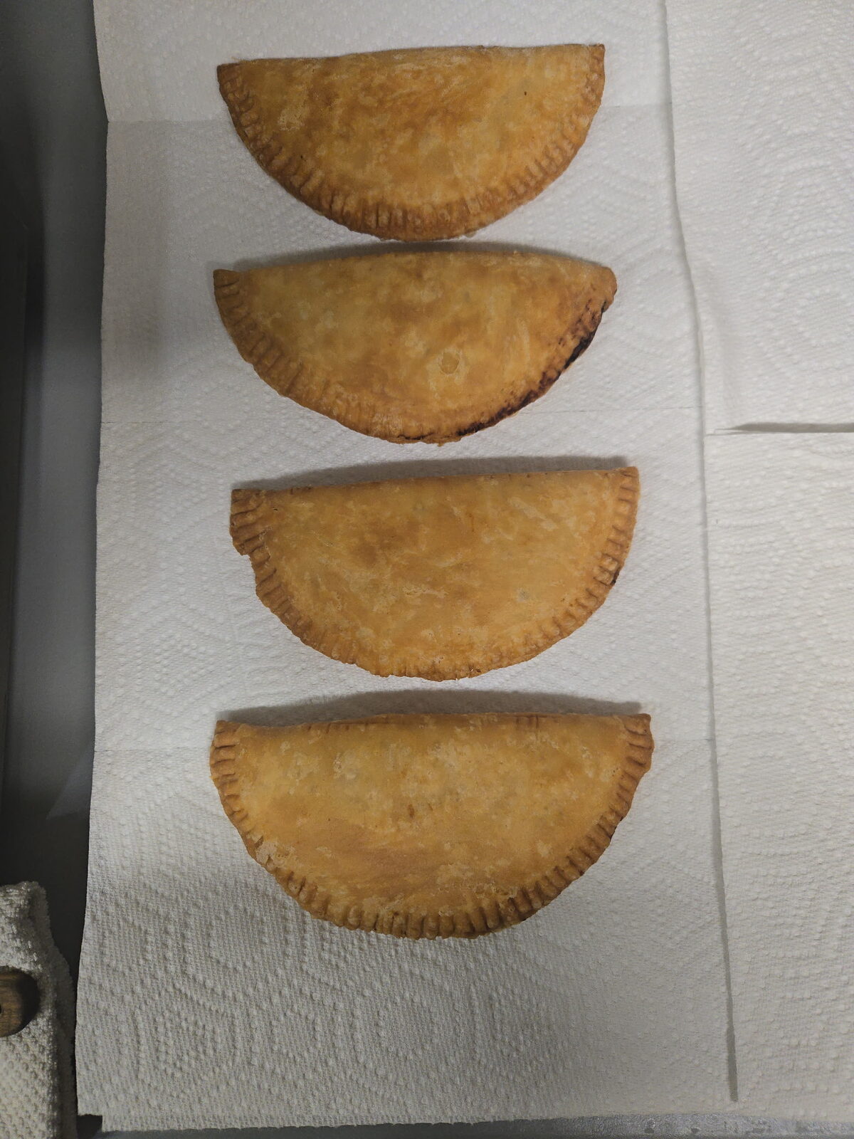 Four freshly fried pies cooling on paper towels